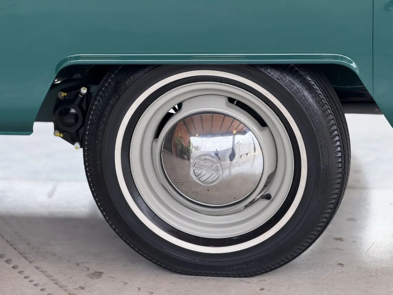 Roda da VW Kombi Luxo 1965 com calota Volkswagen e pneu com faixa branca