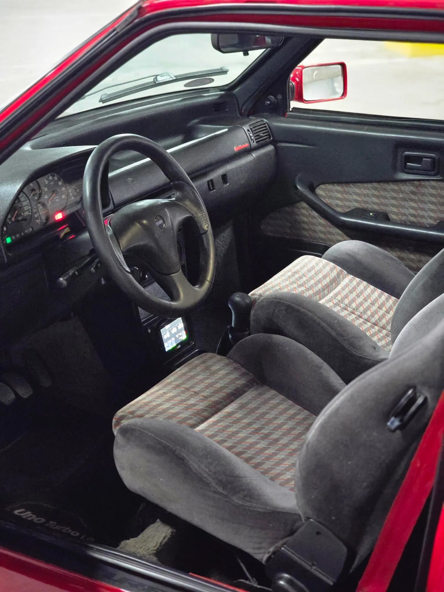 Interior do Fiat Uno Turbo 1994 com volante, painel e banco dianteiro