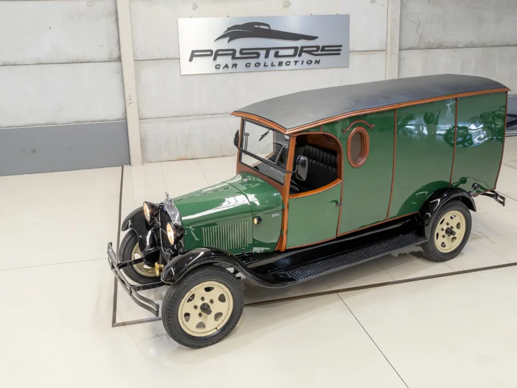 Ford Model A Furgão 1929 verde com para-lamas pretos e acabamento externo em madeira, visto de frente na diagonal