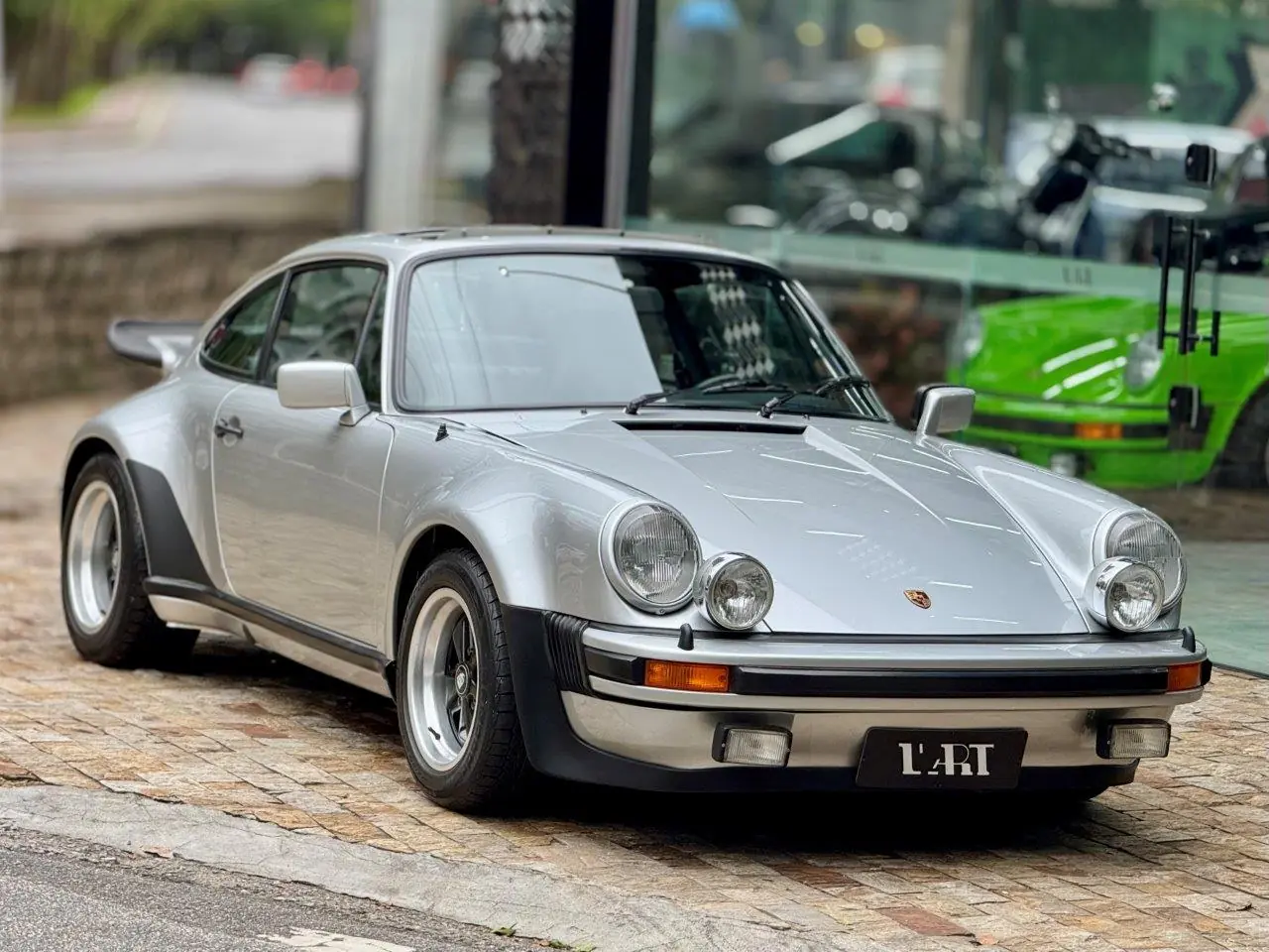 Porsche 930 Turbo 1975 fotografado de frente e em ângulo diante da coleção L'Artbr