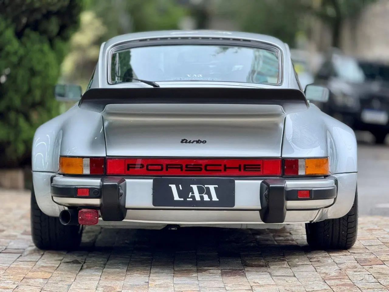 Vista traseira central do Porsche 930 Turbo 1975 destacando pneus largos e asa traseira